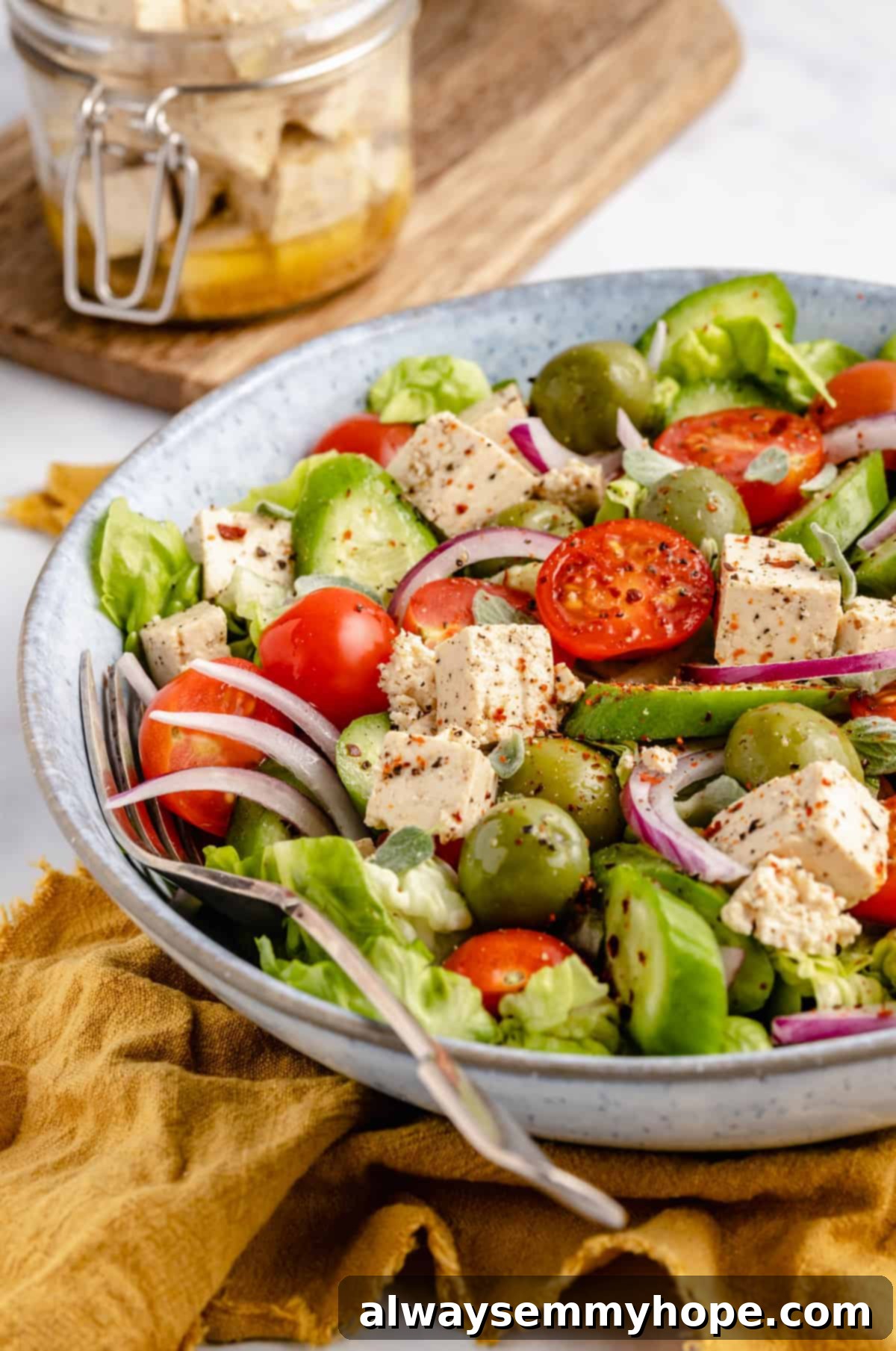 Vegan tofu feta cheese is a quick and easy plant-based substitute that needs only 6 ingredients. Enjoy it on salads, sandwiches, and more! vegan feta cheese in a salad at a side angle