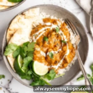 Vegan butter chicken in bowl with rice, naan, and garnishes