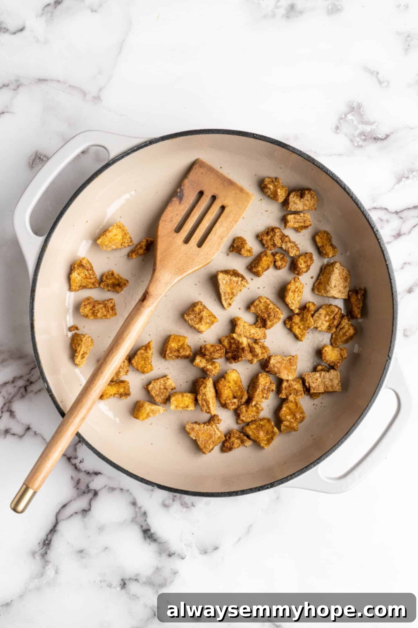 Overhead view of seasoned tofu browning in a Dutch oven, achieving a perfect crispy exterior