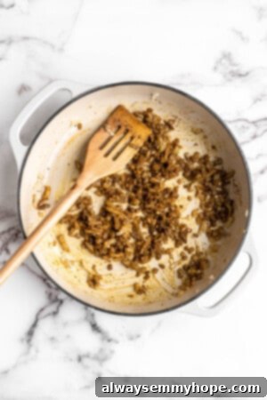 Overhead view of onions infused with aromatic spices in a Dutch oven, showing the rich color and fragrance developing