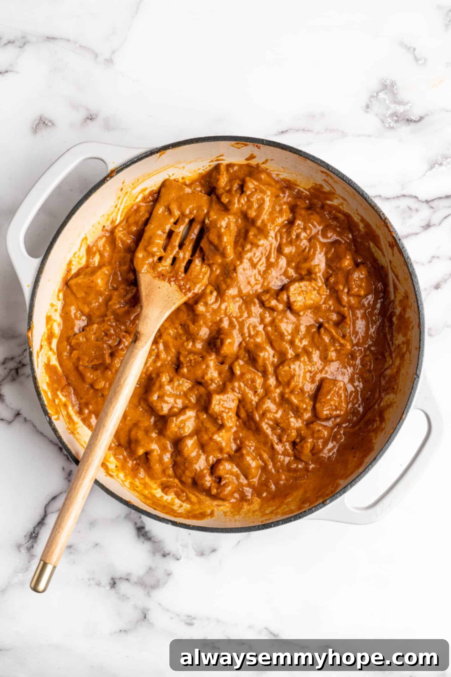 Overhead view of vegan butter chicken with golden brown tofu cubes immersed in the creamy sauce in a Dutch oven