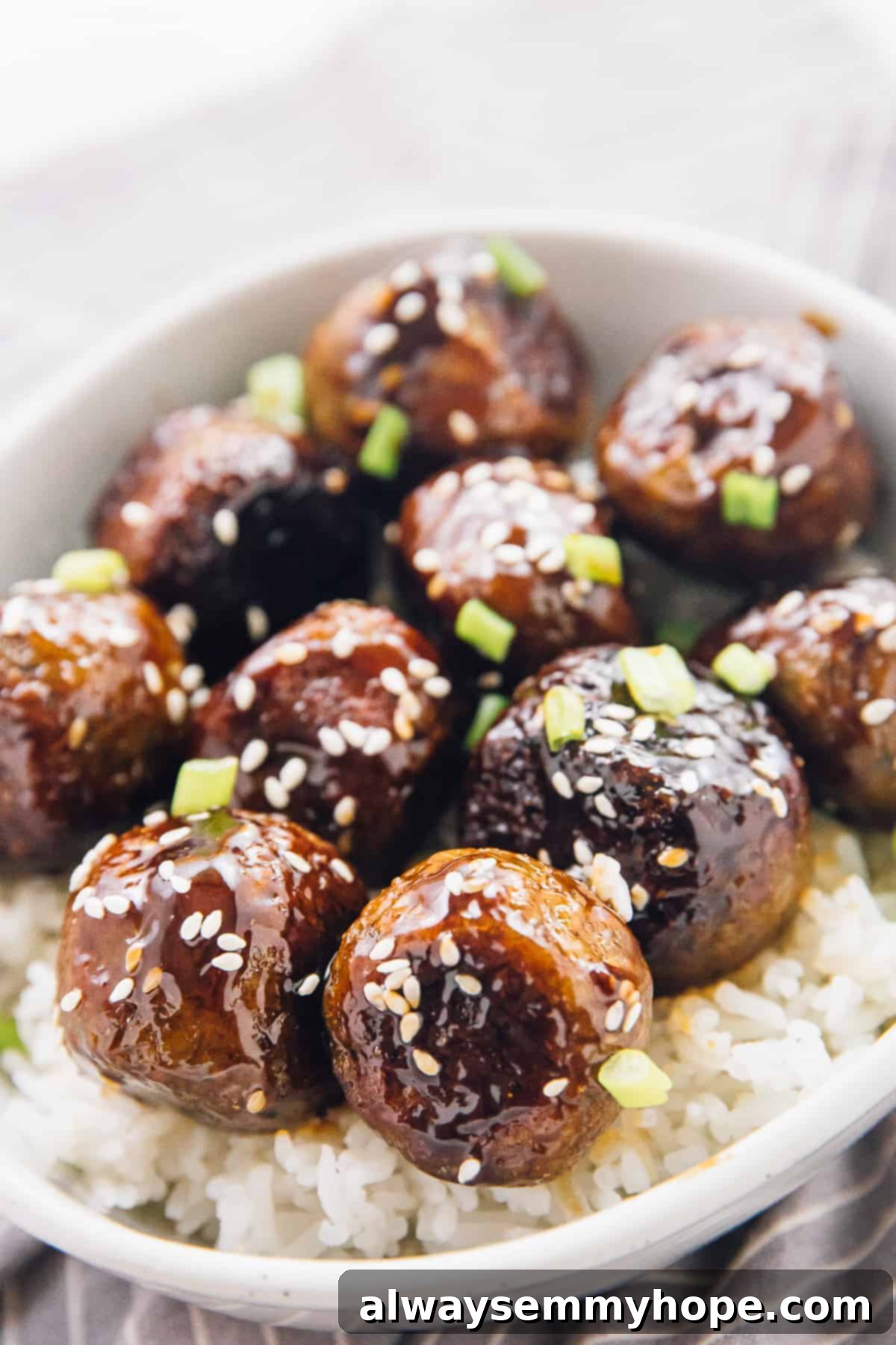 Vegan teriyaki meatballs are easy to make, slathered with flavor-packed homemade teriyaki sauce. Great for dinner, appetizers, or meal prep! Close-up shot of veggie meatballs covered in sauce on a bed of white rice