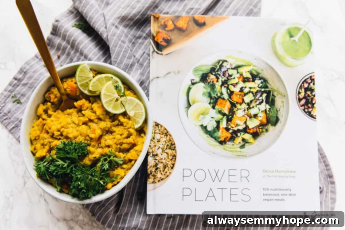 A bowl of kitchari topped with lime and parsley, with a spoon in it, next to a cookbook called "Power Plates"