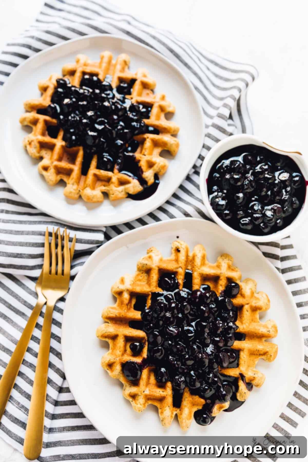 Top down view of fluffy vegan and gluten-free lemon poppyseed waffles with vibrant vanilla blueberry sauce on top.