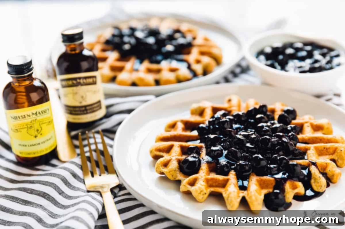 Platter of golden lemon poppyseed waffles, generously topped with a vibrant homemade blueberry sauce and a dusting of poppy seeds.
