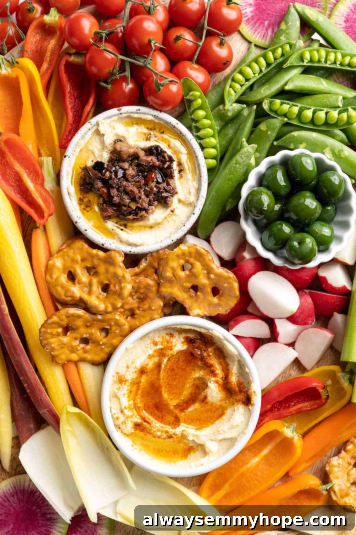 This simple tutorial will show you how to make a perfect vegetable crudité platter that's sure to impress your guests. So easy! Overhead view of crudité platter with bowls of hummus and green olives