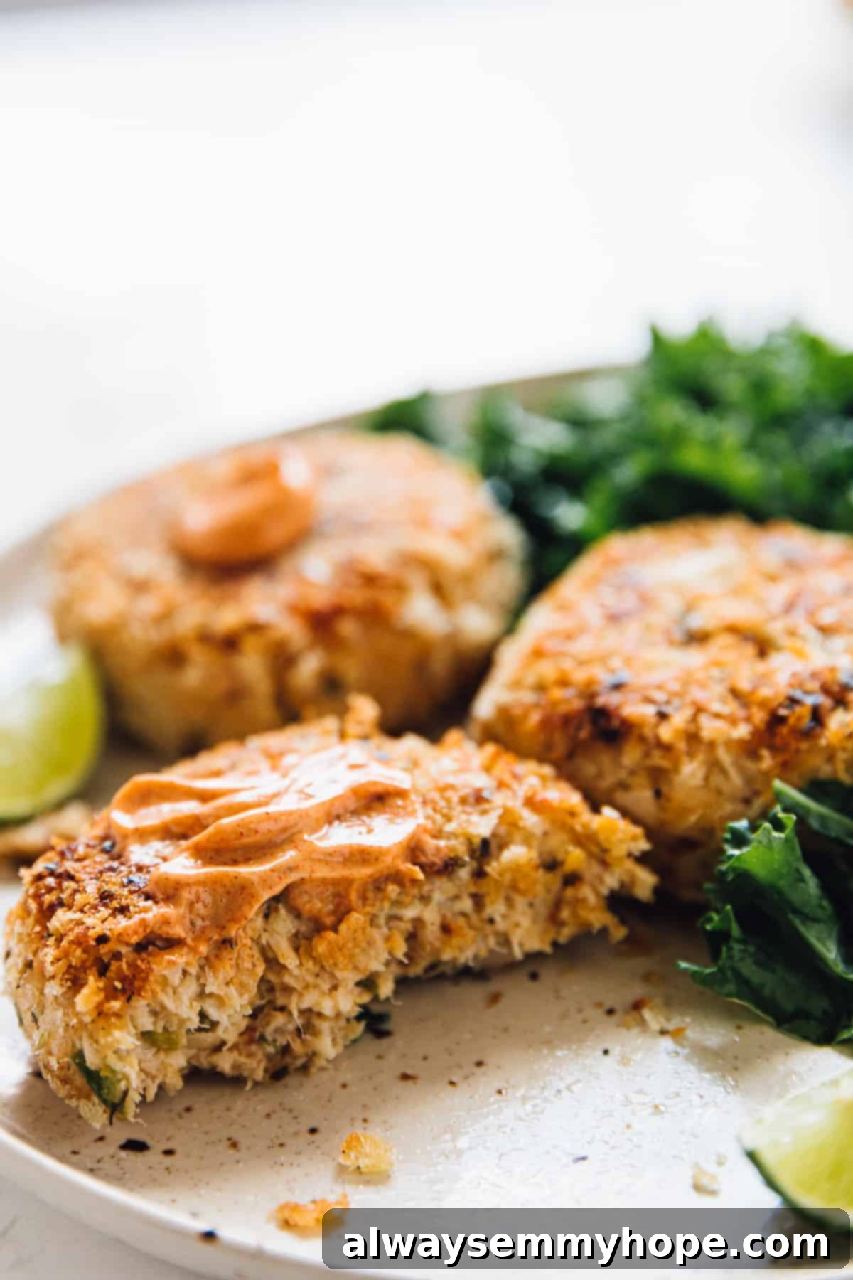 Vegan crab cakes, topped with sauce on a plate with salad on the side.
