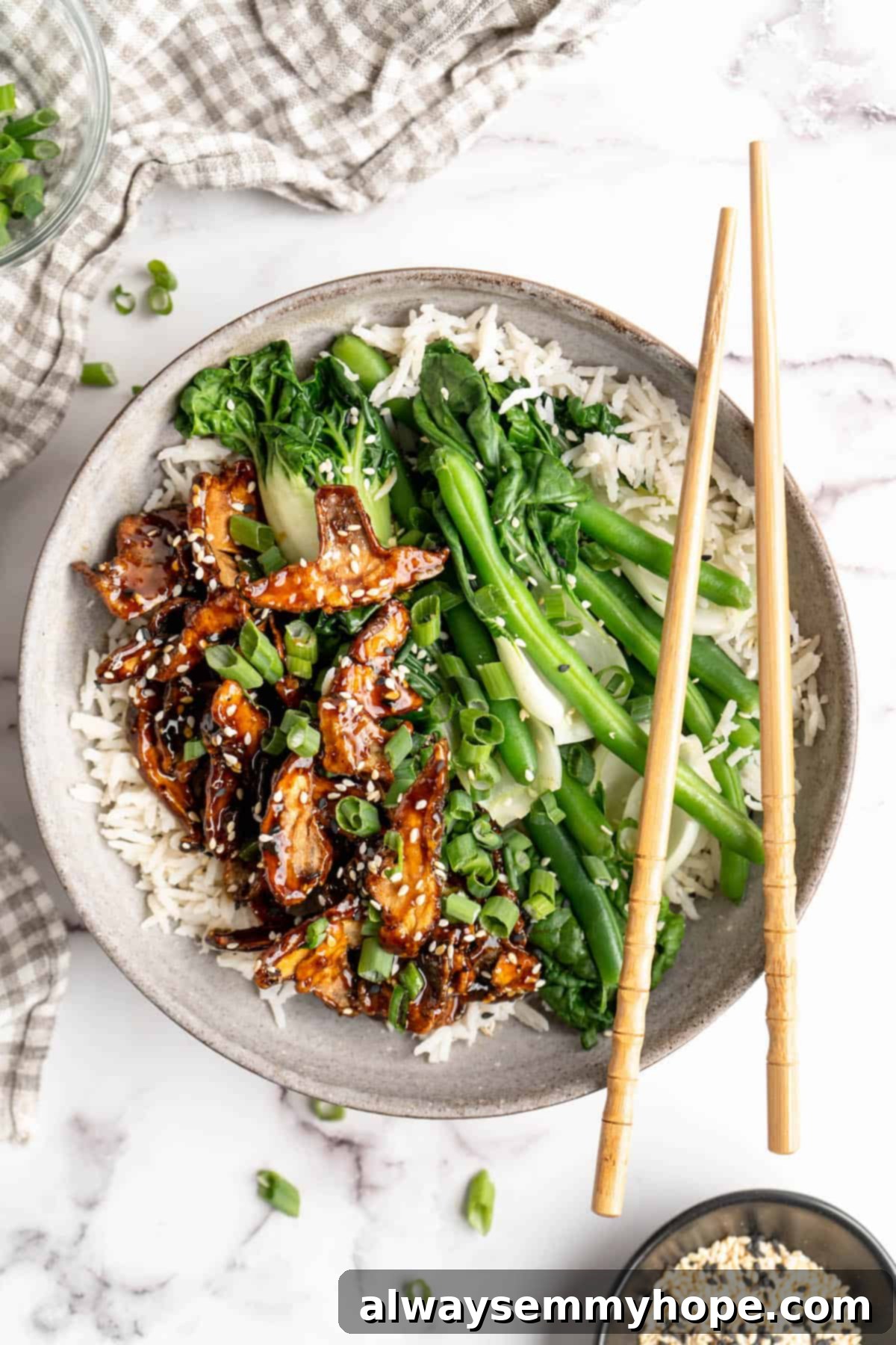 Bowl of rice with sticky sesame shiitake mushrooms, veggies, and chopsticks