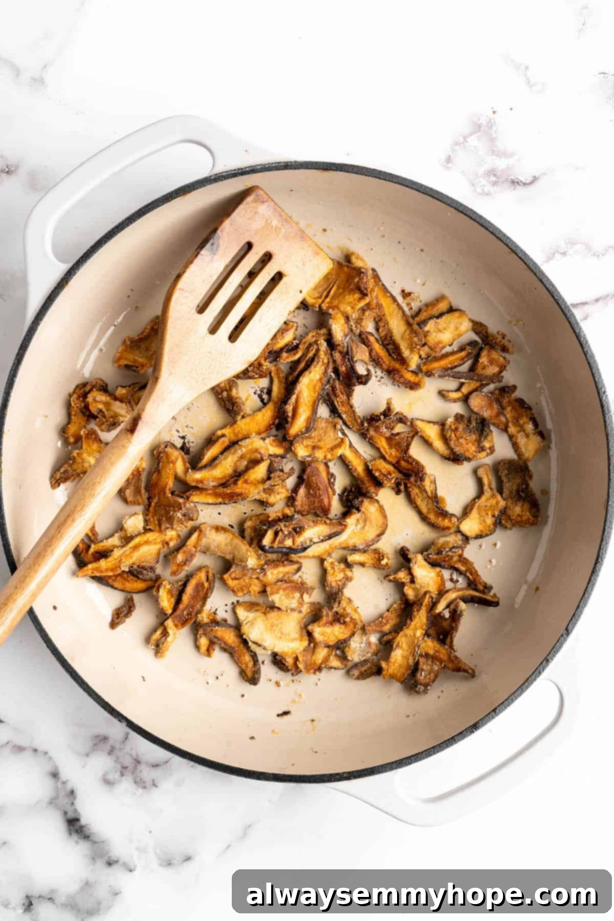 Overhead view of mushrooms being cooked in enamel pan