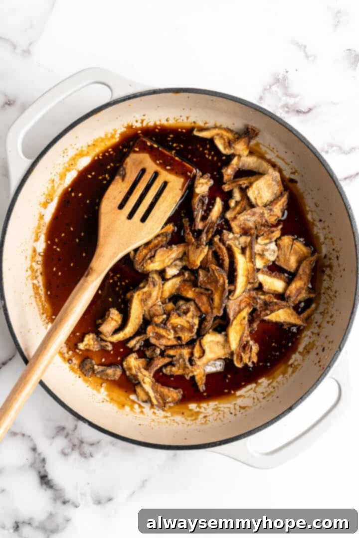 Overhead view of mushrooms added to pan of sauce