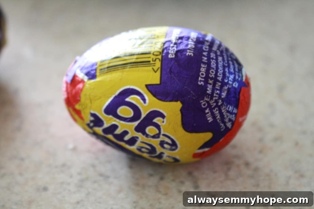 A single, unwrapped Cadbury chocolate egg, displaying its iconic shape and rich chocolate shell, poised to be hidden within a cupcake.