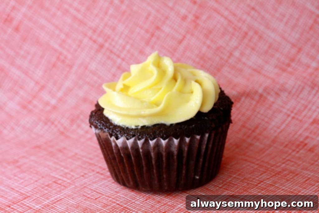 A close-up side view of a beautifully frosted chocolate cupcake with bright yellow cream cheese frosting, ready for an Easter celebration.