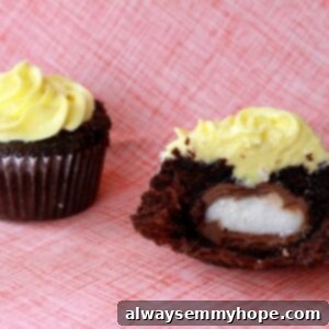 Two festive chocolate Cadbury Egg cupcakes, with bright yellow frosting, placed on a pink tablecloth, ready to be enjoyed.