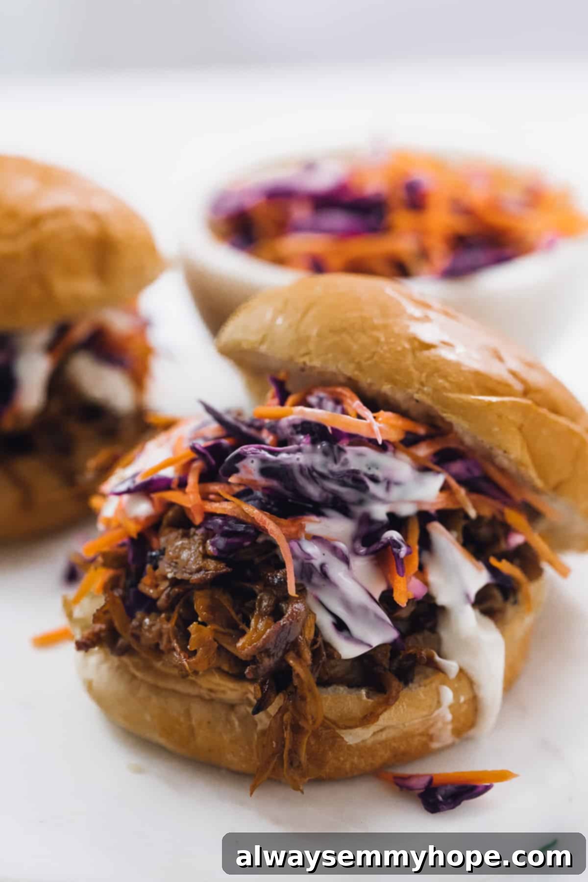 Smoky Vegan Pulled Mushroom Sandwiches 5 A close up of a vegan pulled mushroom sandwich with sauce and slaw..