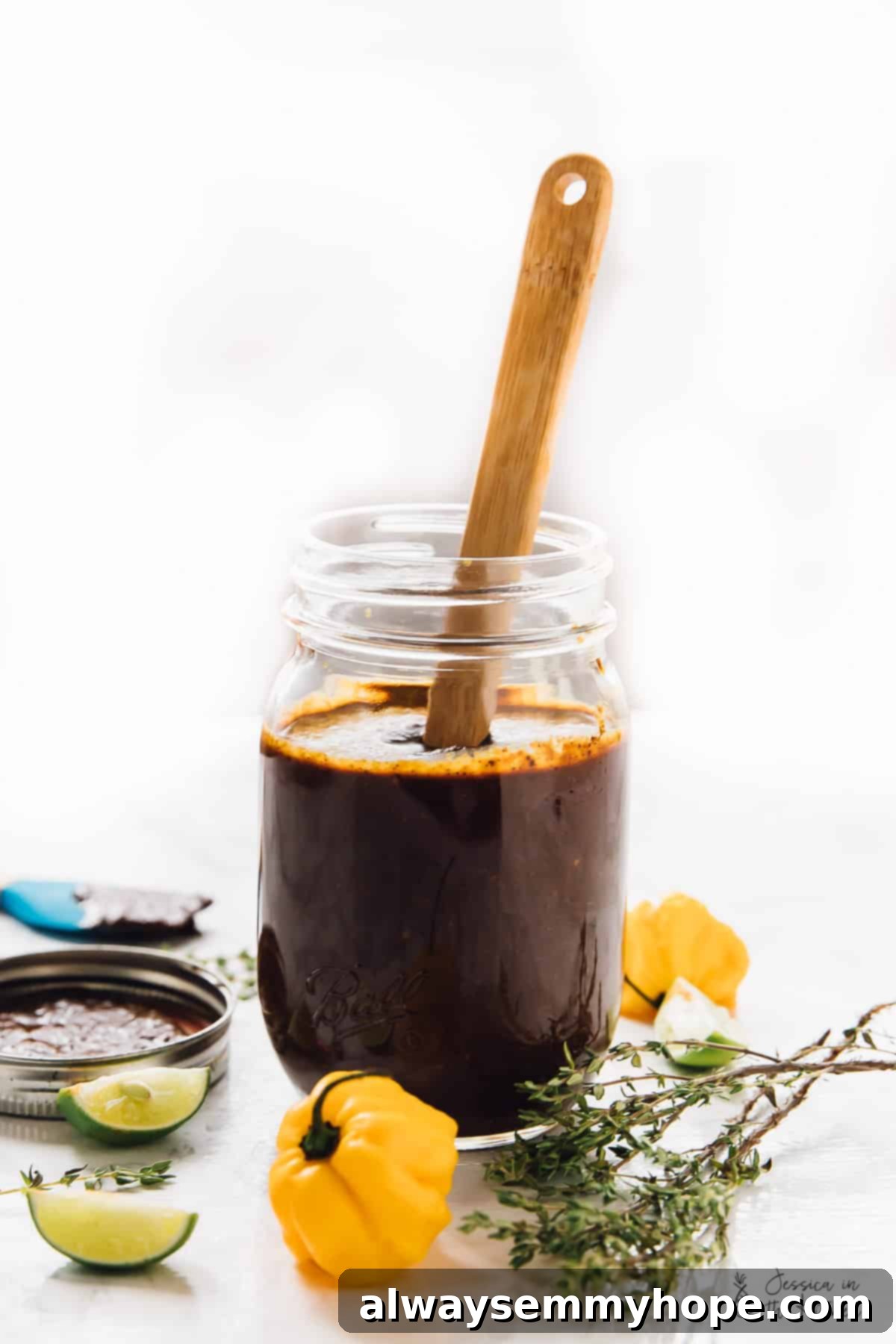 Easy Homemade Jamaican Jerk Sauce 4 A jar of homemade Jamaica Jerk Sauce in a rustic setting with fresh scotch bonnet peppers and thyme sprigs.