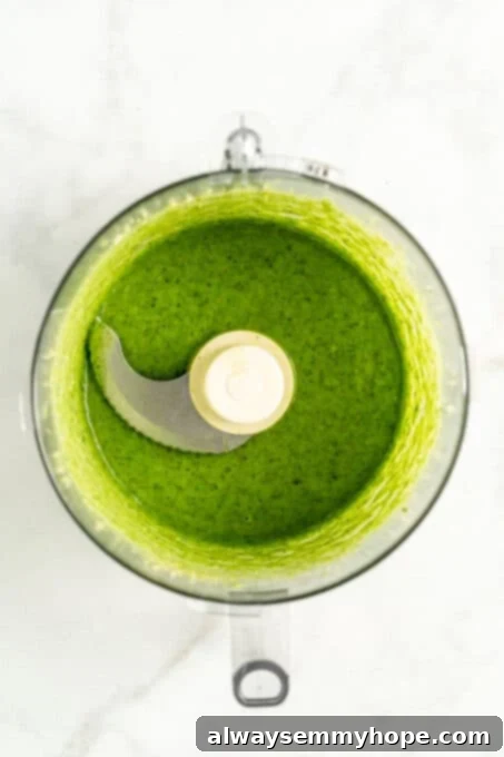 Overhead view of vibrant green pesto inside food processor with lid removed