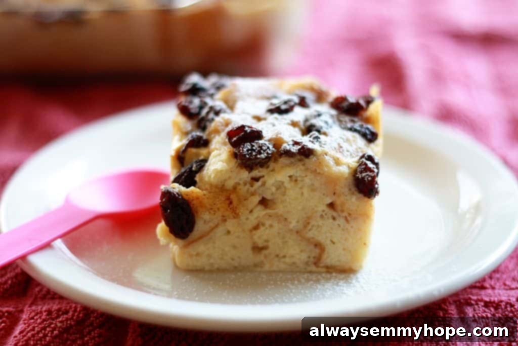 A very traditional bread pudding with raisins, for my brother's birthday! With powdered sugar and rum, this one's sure to please. Side shot of a square of dessert with raisins on a white plate.