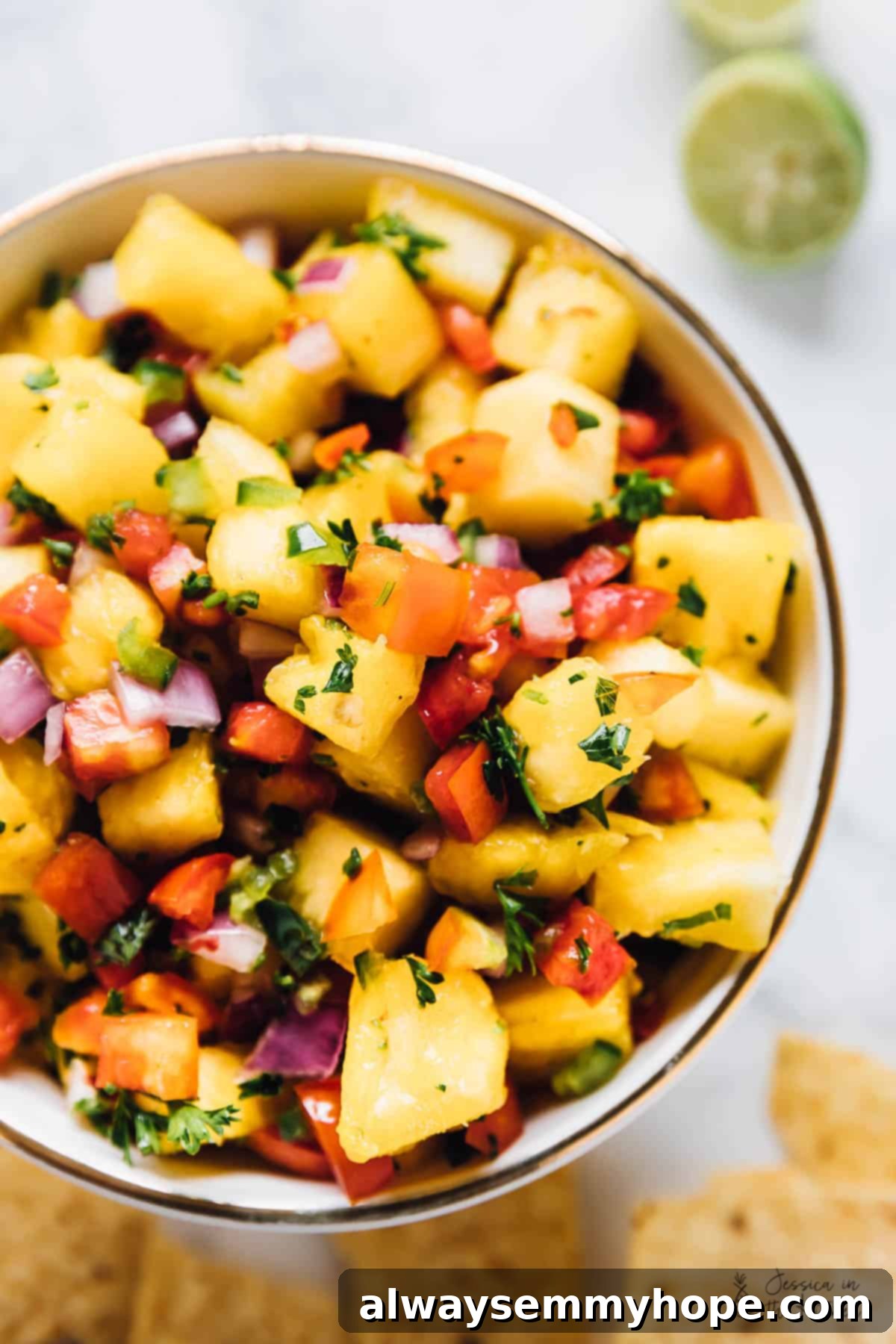 This fresh pineapple salsa recipe with jalapeño, parsley, tomatoes, and onions is the perfect sweet-and-tangy condiment for taco night. Parsley-pineapple salsa with onions, tomatoes, and jalapeños in a bowl, ready to be served.