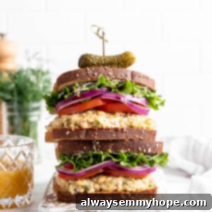 Creamy Vegan Chickpea Tuna Salad 8 Two stacked vegan tuna sandwiches topped with sprouts, lettuce, red onion, and tomatoes
