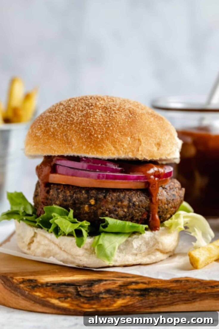 10 Irresistible Vegan BBQ Recipes for Grilling Season 3 Hearty Black Bean and Quinoa Burgers, served on buns with a vibrant, homemade Strawberry BBQ Sauce.