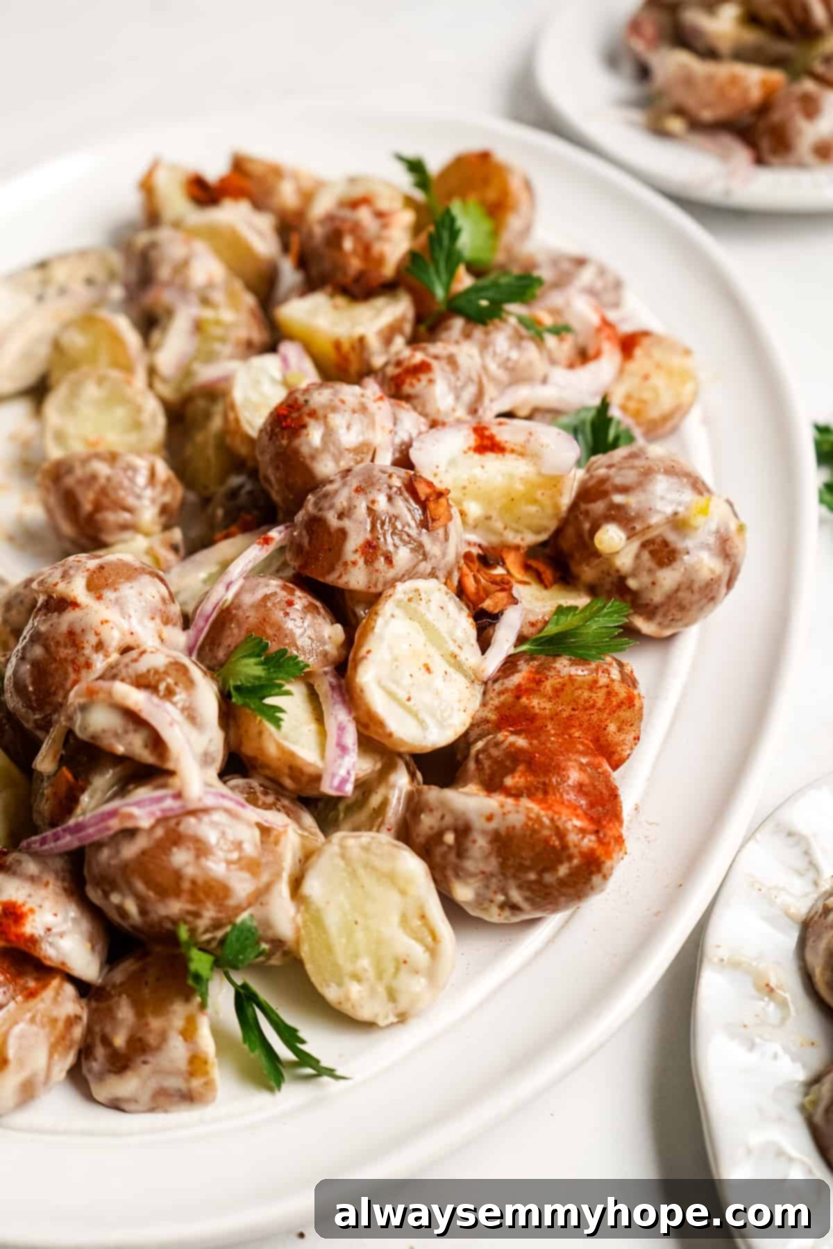 Creamy Vegan Potato Salad topped with crispy coconut bacon and fresh herbs.
