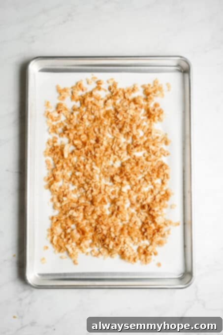 Seasoned coconut flakes spread evenly on a baking sheet.