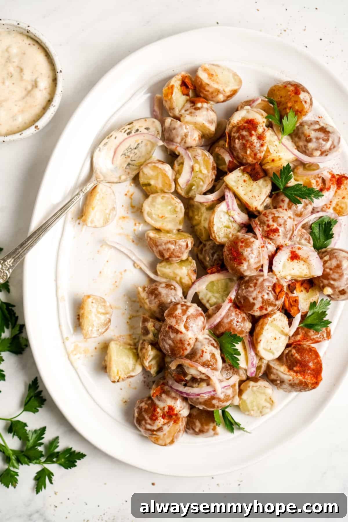 A spoon resting on a plate of vegan potato salad, elegantly sprinkled with paprika.