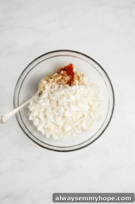 Unsweetened coconut flakes in a mixing bowl with liquid seasonings.