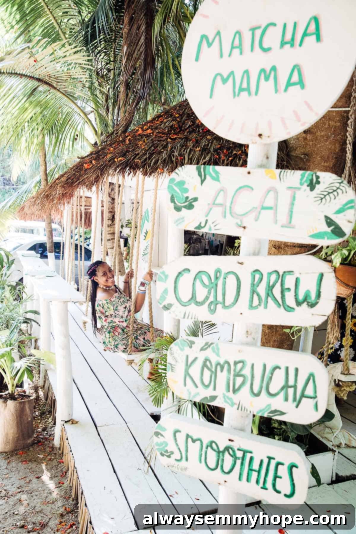 Jessica on a swing under palm trees, overlooking a stunning beach.
