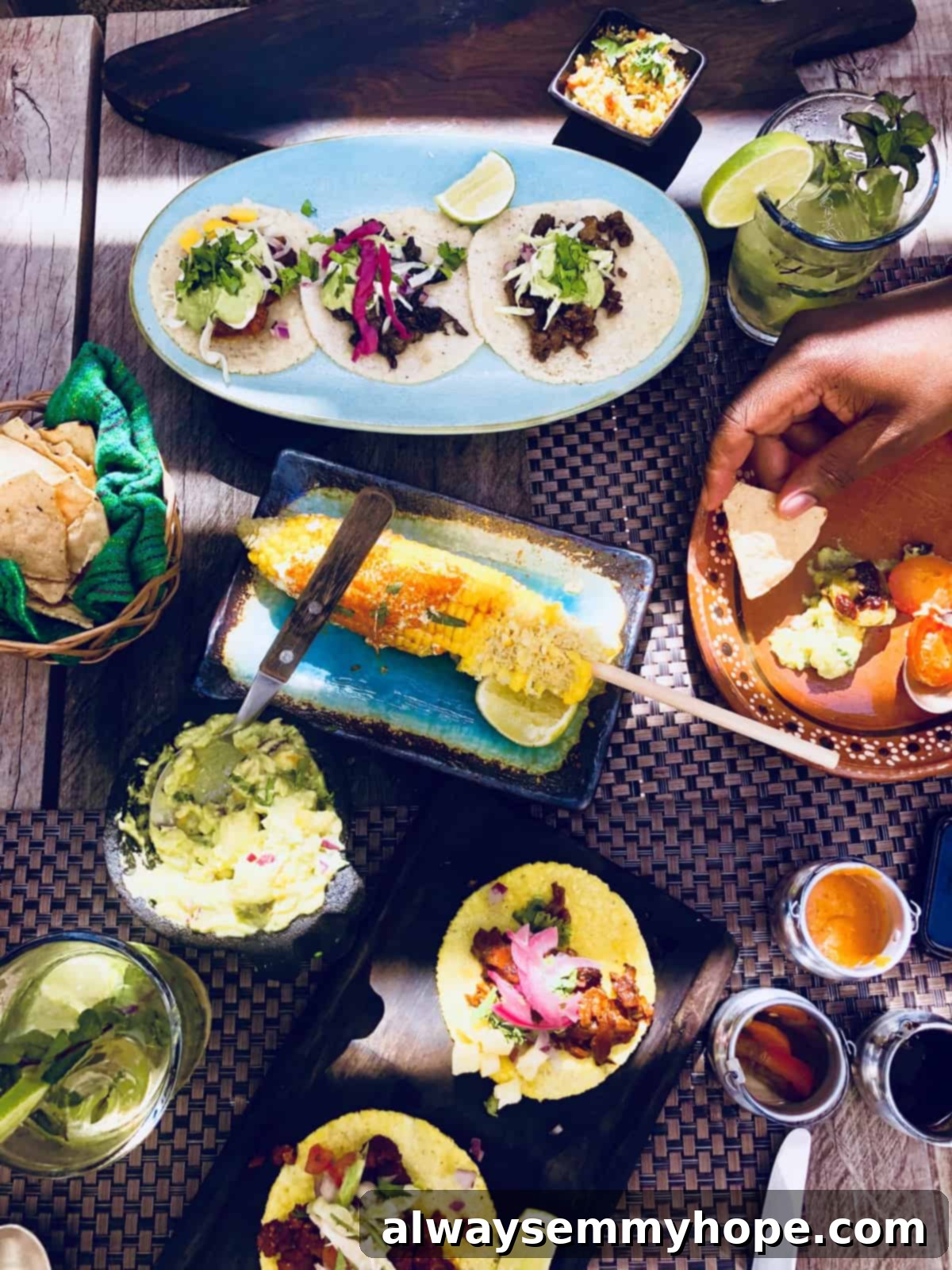 Top down view of various delicious and colorful plates of vegan food, artfully arranged on a wooden table.