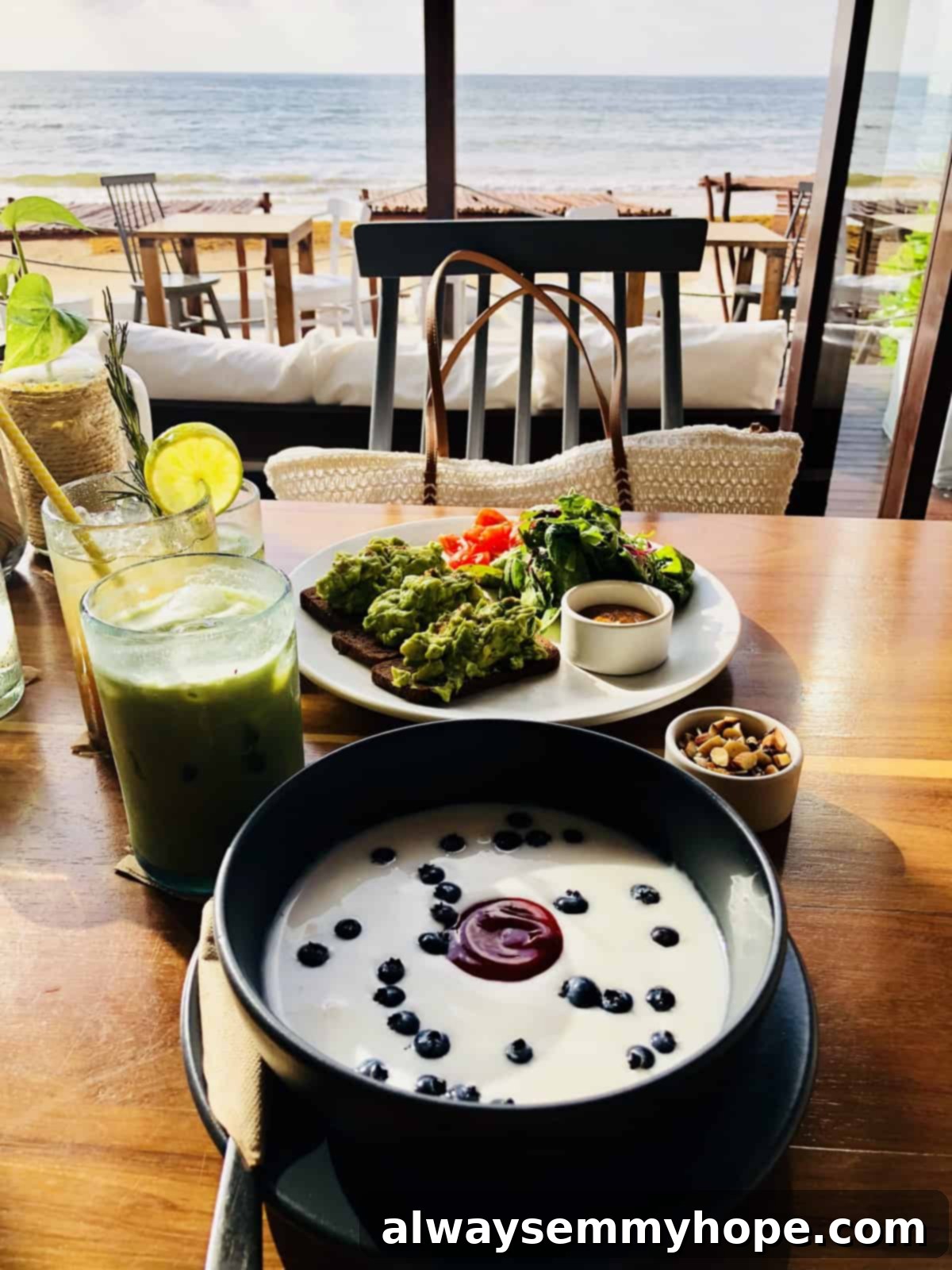 A vibrant bowl of soup elegantly placed on a restaurant table, with the serene beach and ocean visible in the background.