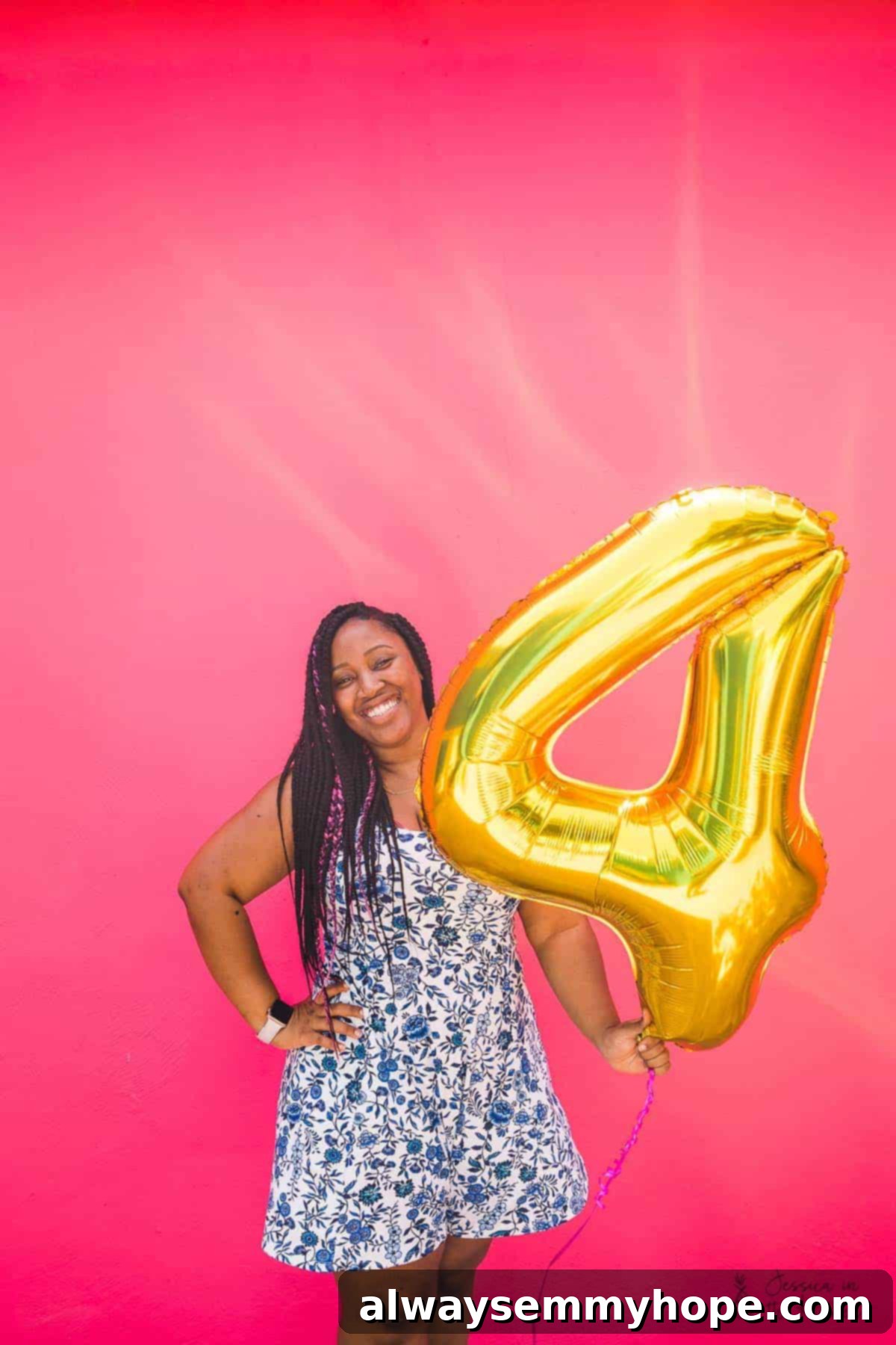 Jessica smiling warmly and holding a large gold number four balloon up close, expressing gratitude on her blog's anniversary.