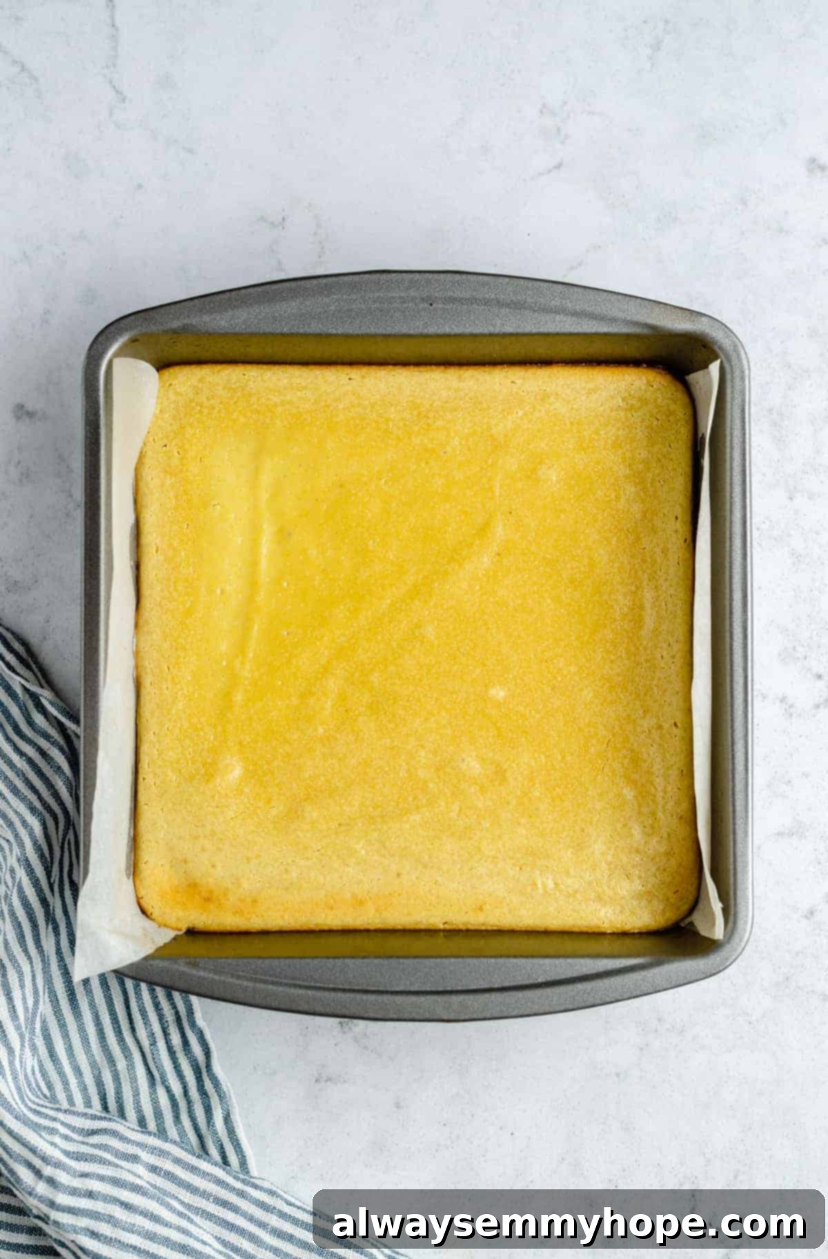 Freshly baked vegan lemon bars in a pan, showing a slightly golden and set surface.