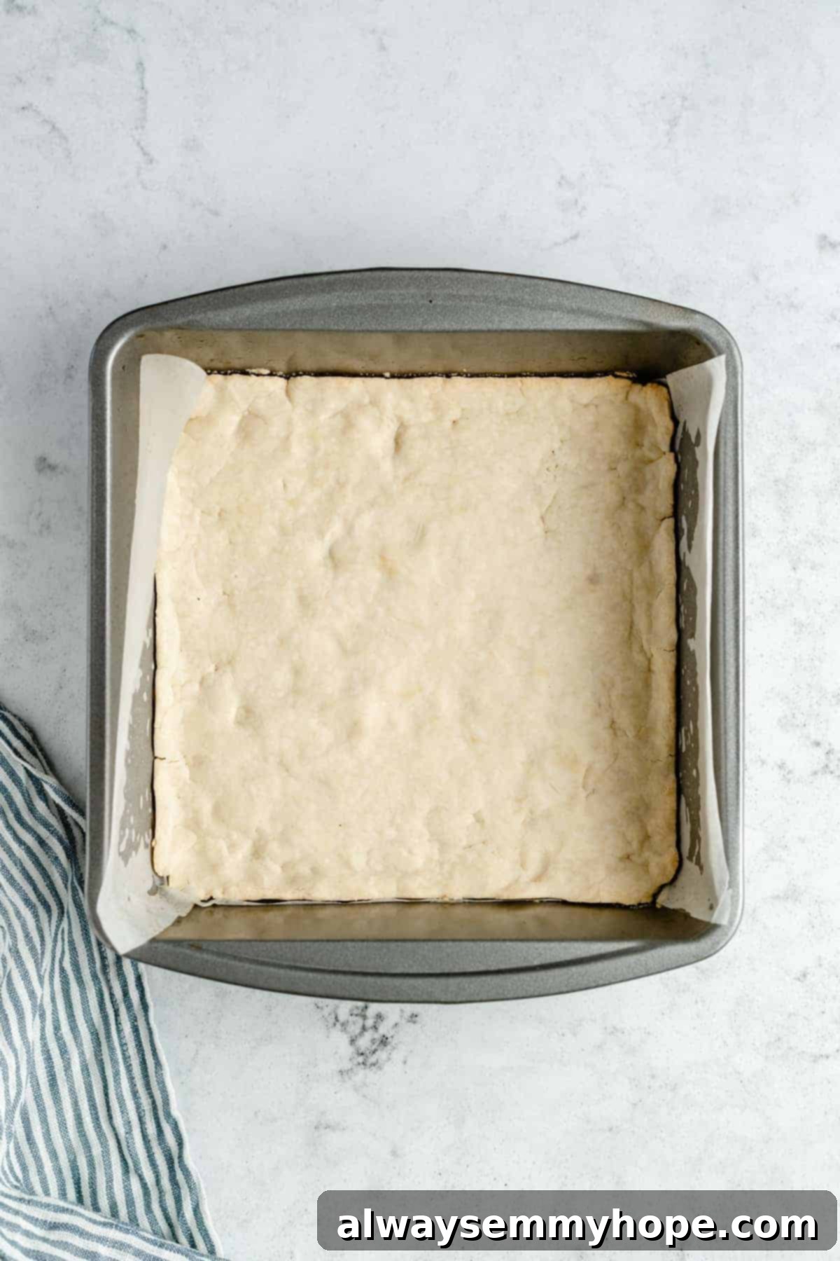 Baked shortbread crust cooling in a parchment-lined pan.