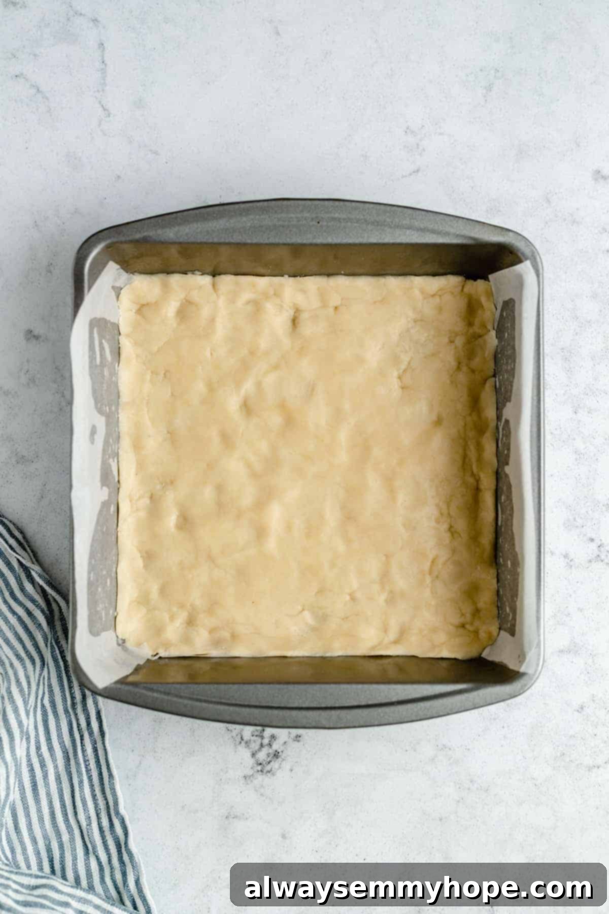 Par-baked shortbread crust in a pan, ready for the lemon filling.