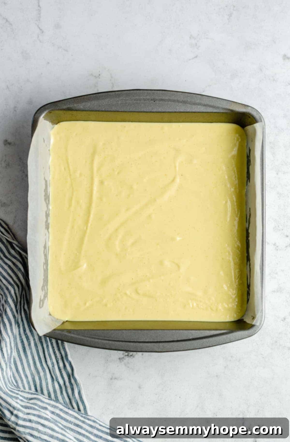 Unbaked vegan lemon bars in a pan with the filling spread evenly, ready for the oven.