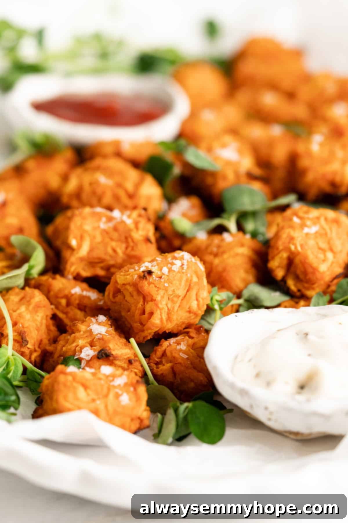 Closeup view of a single sweet potato tot, showing its crispy exterior and soft interior, on a serving platter