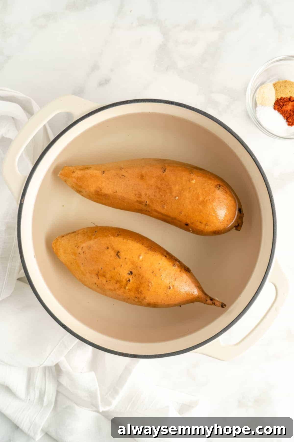 Overhead view of whole sweet potatoes being parboiled in a large pot of boiling water