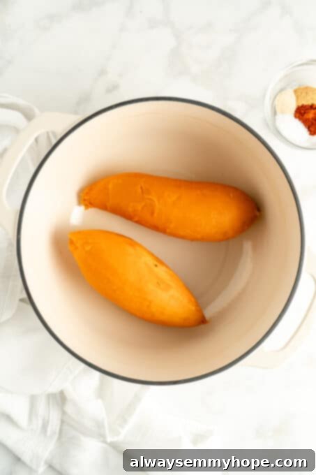 Overhead view of cooked and peeled sweet potatoes in a white pot, ready for grating