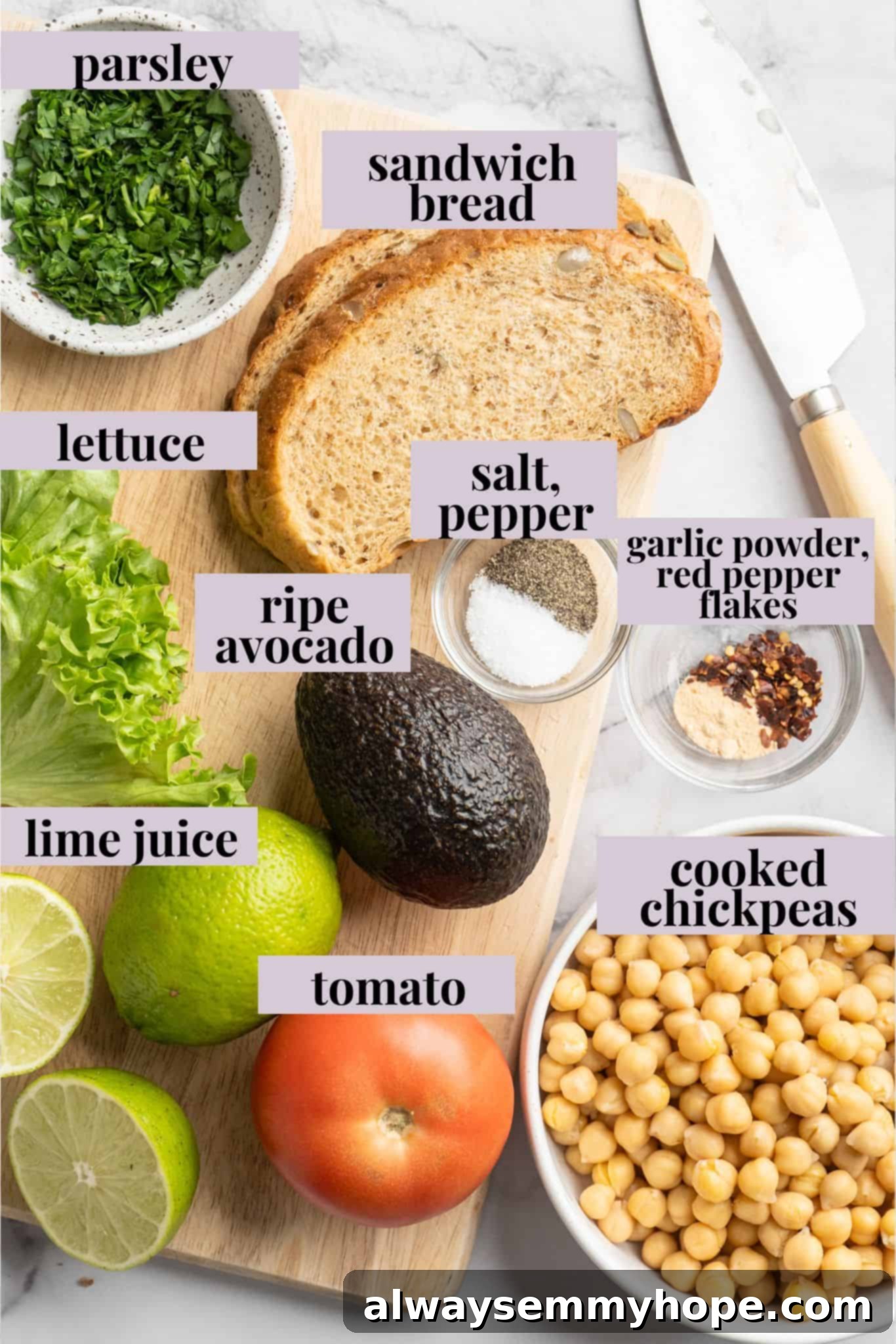 Overhead view of fresh ingredients for smashed chickpea avocado salad sandwich laid out on a wooden cutting board.