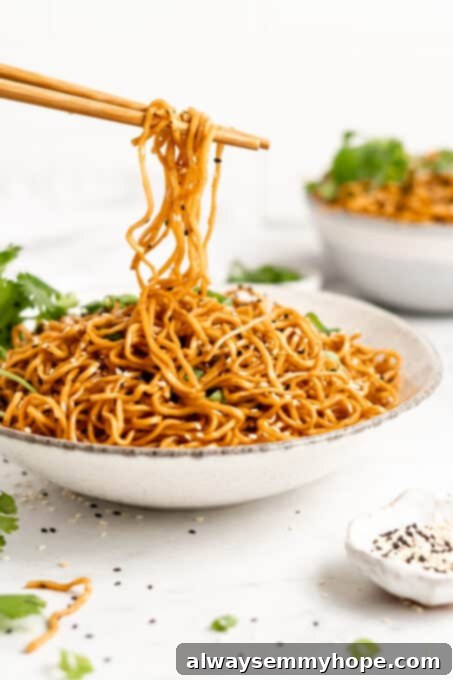 Chopsticks holding a delicious tangle of vegan sesame noodles.