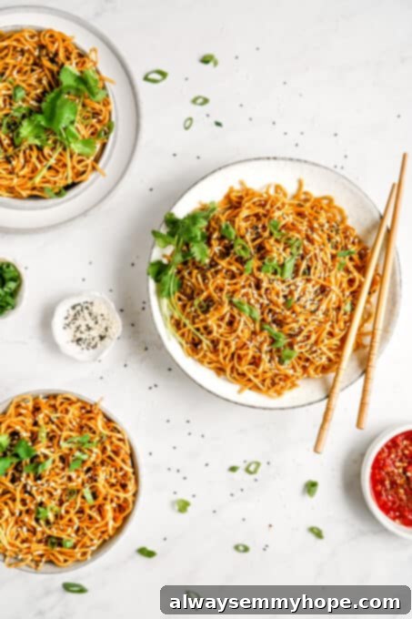 A generous plate of vegan sesame noodles, garnished and ready to be enjoyed with chopsticks.