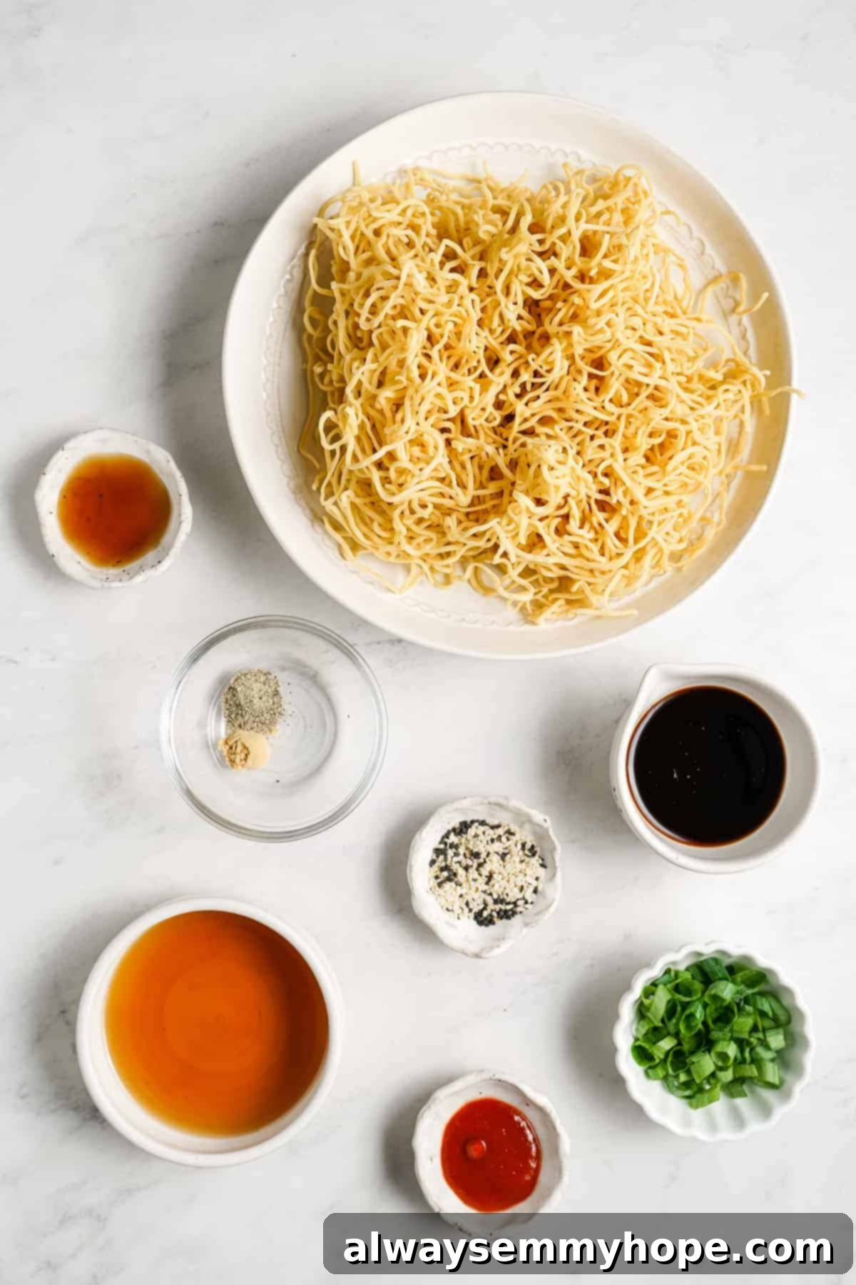 A selection of fresh ingredients laid out, including maple syrup, liquid aminos, sesame seeds, and ginger for vegan sesame noodles.