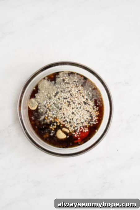Close-up of maple syrup, sesame seeds, and liquid aminos being measured and mixed in a bowl.