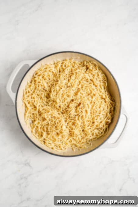 Close-up of perfectly sautéed noodles in a pan, slightly browned and ready for sauce.