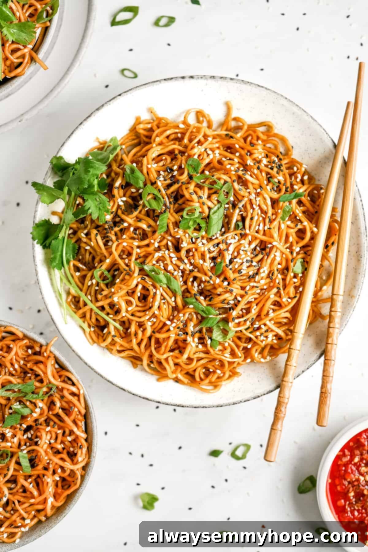 A vibrant plate of vegan sesame noodles garnished with sesame seeds and fresh scallions.