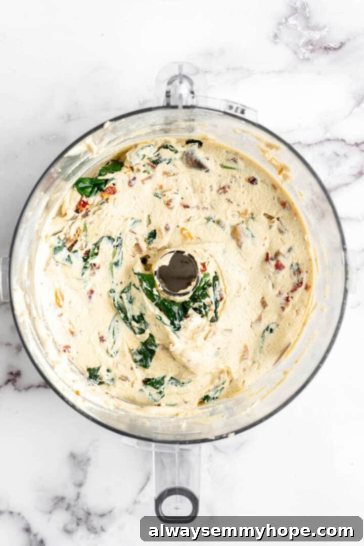 Close-up of the vegan quiche mixture with vegetables and chives thoroughly combined in a food processor.