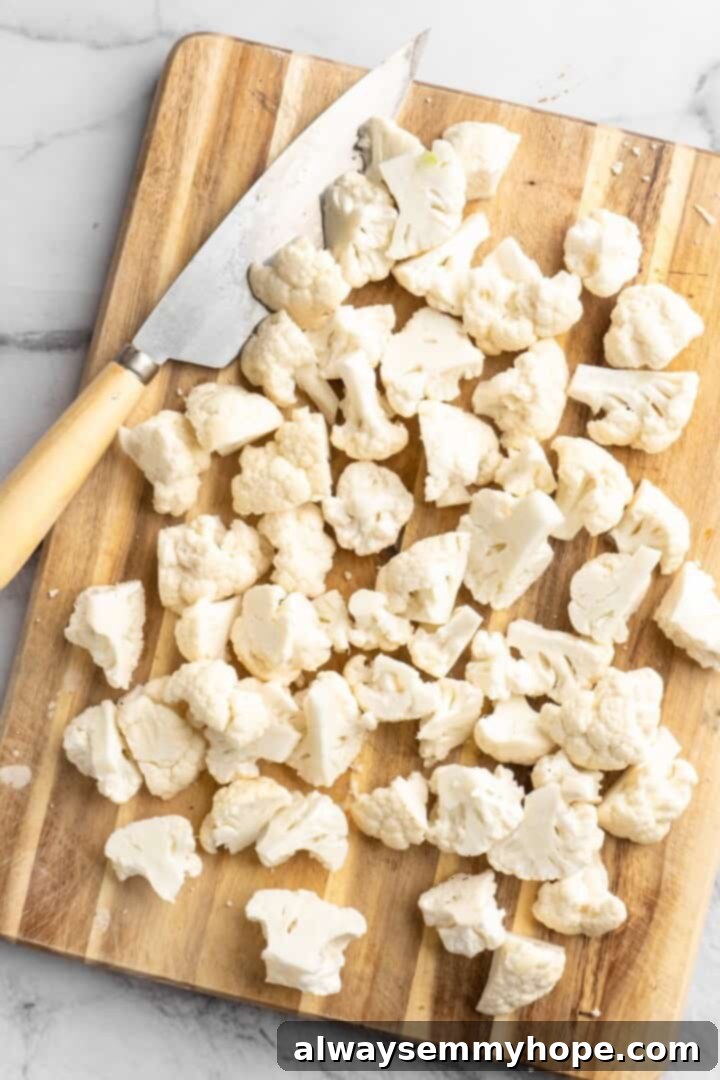 Cutting Cauliflower Florets Overhead view of cauliflower cut into florets on wooden board with knife