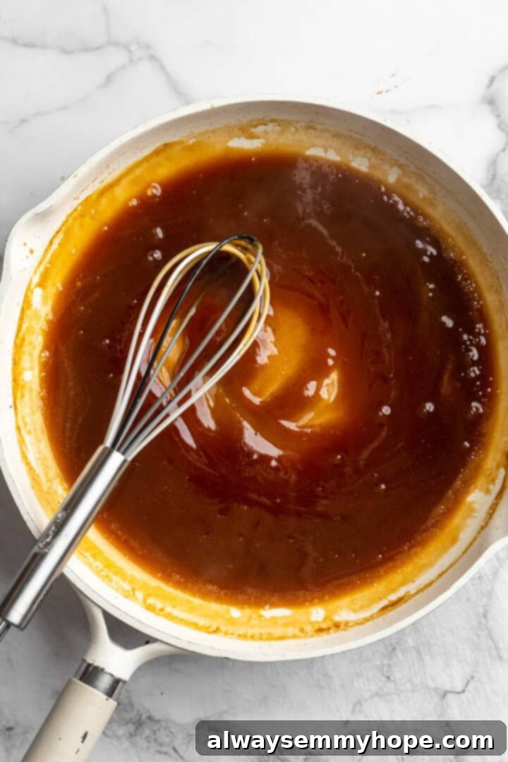 Simmering the Homemade Orange Sauce Overhead view of orange sauce in pan with whisk
