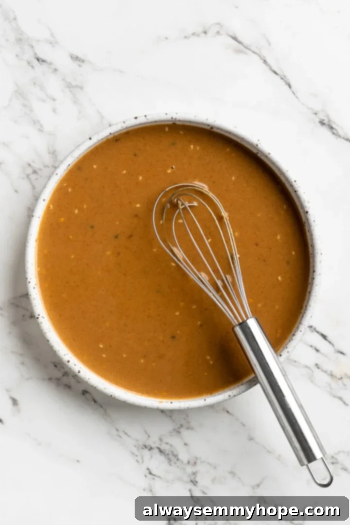 Overhead view of peanut sauce in bowl with whisk